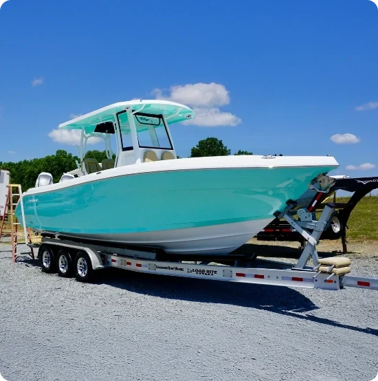 light blue and-white center console boat on a trailer under clear sky
